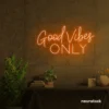 Orange neon Good Vibes Only sign glowing warmly in a room.