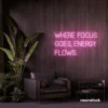 Where Focus Goes Energy Flows neon sign in baby pink for productivity decor and creative inspiration.
