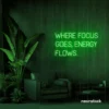 Where Focus Goes Energy Flows neon sign in deep green for productivity decor and creative inspiration.