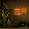 Where Focus Goes Energy Flows neon sign in orange for productivity decor and creative inspiration.