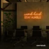 Work Hard Stay Humble neon sign in orange for success-driven decor, workspaces, and personal growth rooms.
