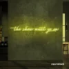 The Show Must Go On neon sign in lemon yellow for stage decor, creative rooms, and dramatic interiors.