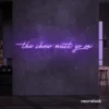The Show Must Go On neon sign in purple for stage decor, creative rooms, and dramatic interiors.